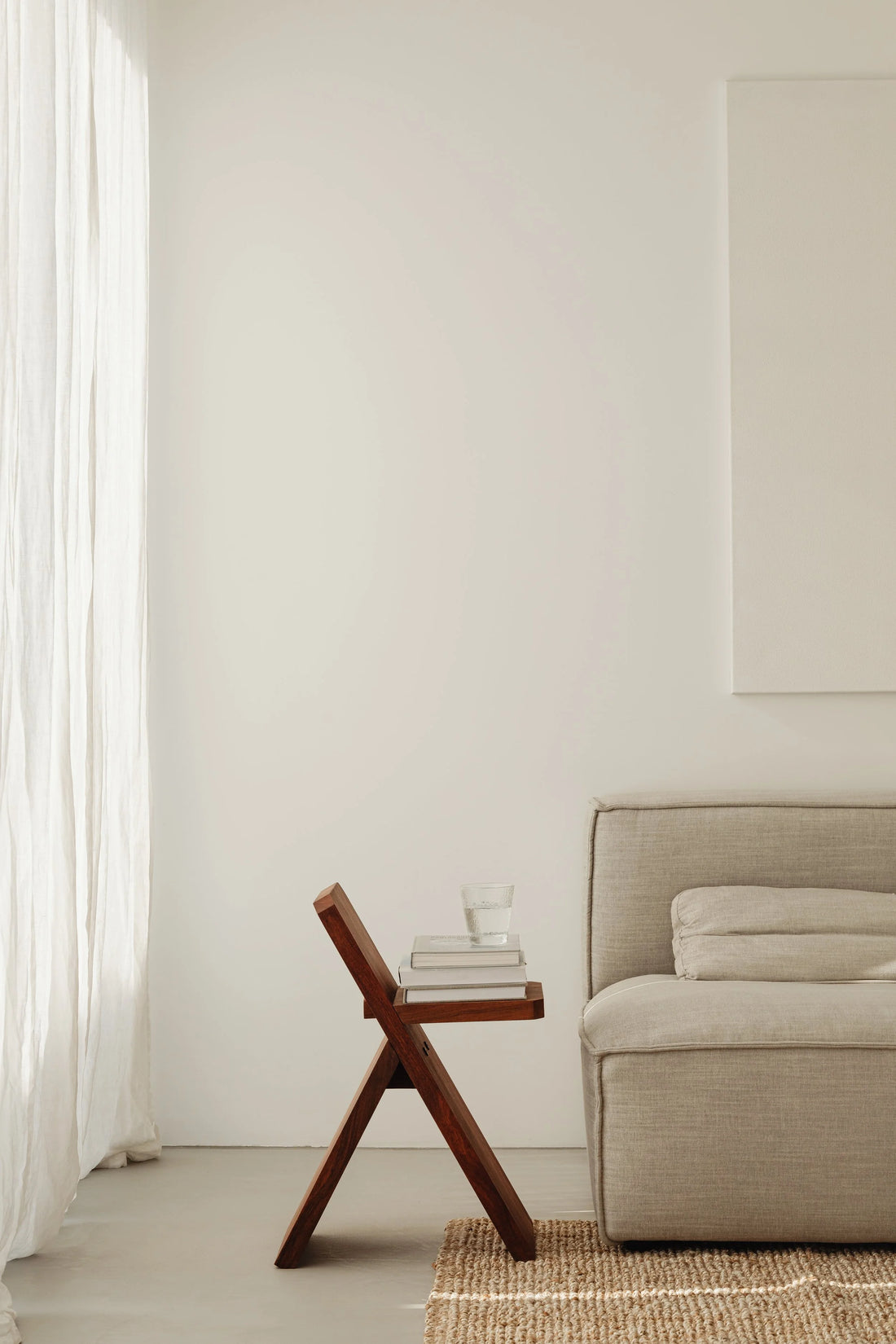 A minimalist room with a wooden chair and a cream sofa