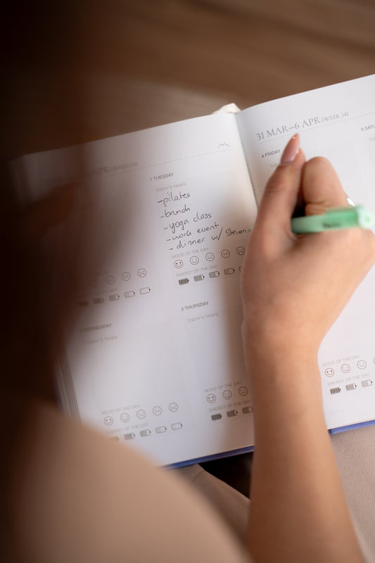 A hand writing the week's plans in a Levitate planner